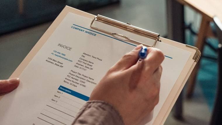 An invoice on a clipboard being checked