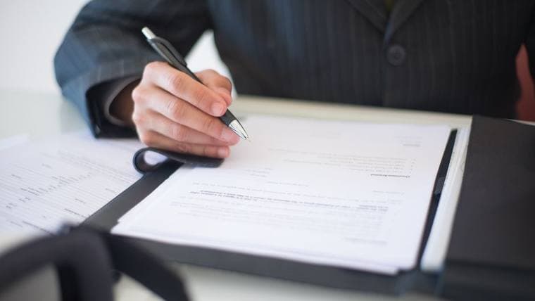 A person signing a document at a desk