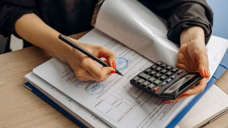Hands working through a ledger with a calculator